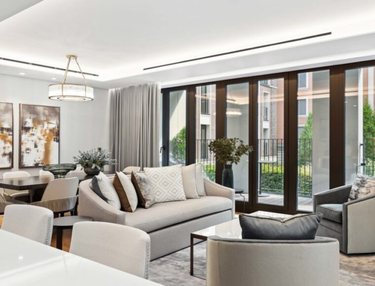 Lounge room with multiple chairs, dining table and a balcony with sliding doors and curtains.