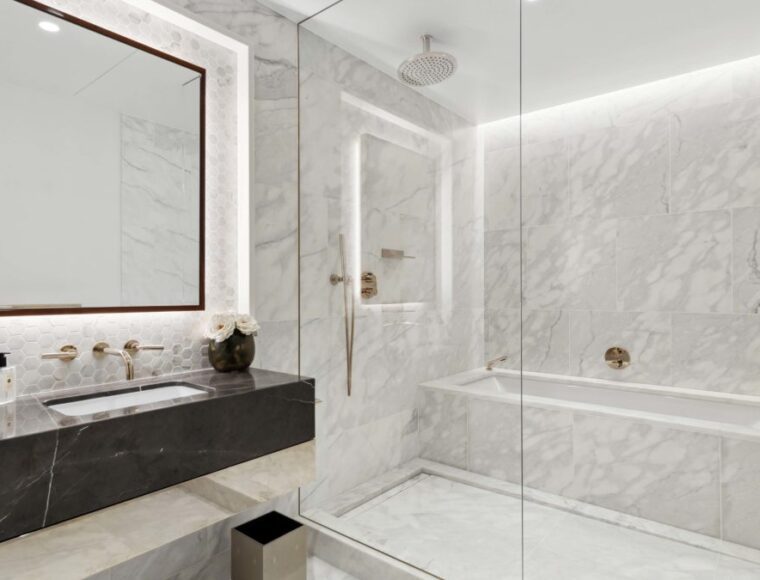 White marble bathroom with a walk-in bath and shower and a large mirror.